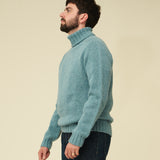 Man wearing a teal sweater against a beige background