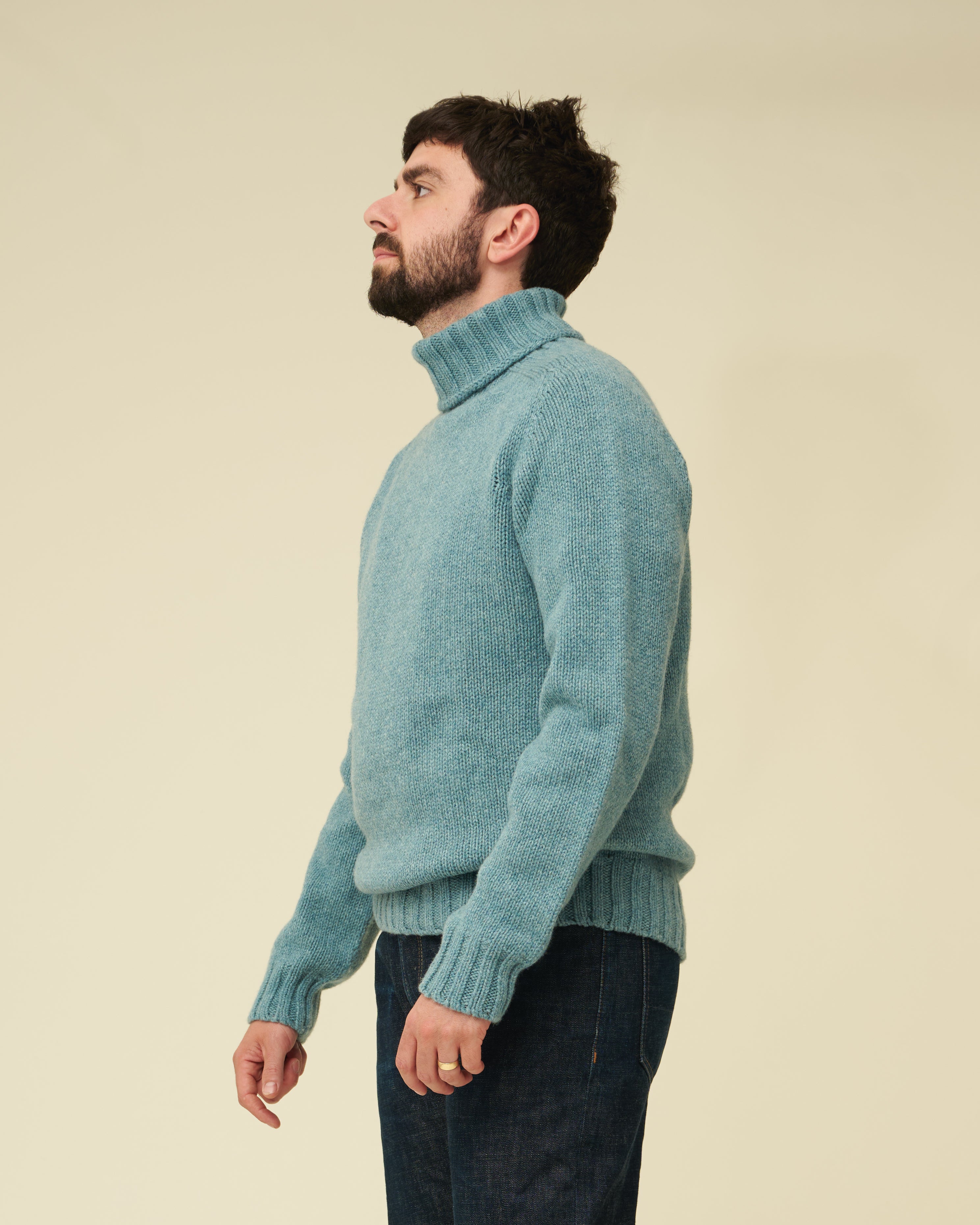 Man wearing a teal sweater against a beige background